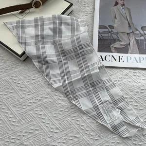 Detail shot of grey plaid cotton scarf with lace brand label and washing instructions tag