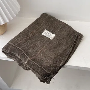 Detailed texture of dark coffee cotton linen scarf with vintage brand label on soft fabric