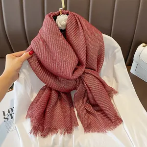 Detail showing red crinkled linen scarf with gold metallic glitter and frayed edges