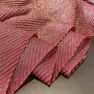 Macro detail of rose red pleated fabric with woven gold metallic glitter threads