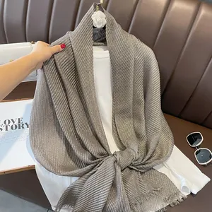 Detail of light gray crinkled linen shawl with metallic gold threads and tassel edges