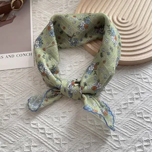 Floral light green silk scarf for women with blue wavy edges on a white texture background