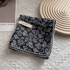 Floral paisley square scarf with white lace trim on a wavy wooden display tray
