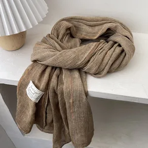 Detail showing soft linen texture and brand label on a khaki pleated scarf