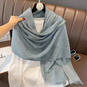Detail of light blue pleated scarf with shimmering gold dust finish and fringe edges