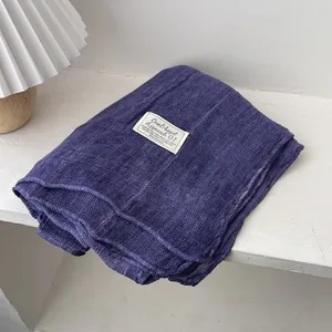 Detailed texture of dark purple cotton linen scarf with a minimalist white brand label
