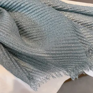 Detail of light blue pleated scarf with silver metallic glitter and frayed edges