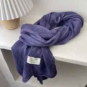 Close-up of soft purple cotton linen scarf featuring a textured knit and stitched label