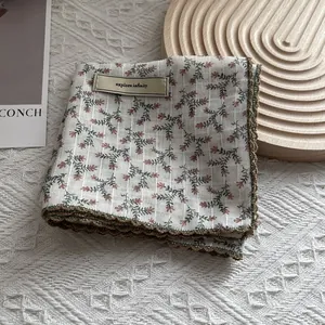 Detailed close-up of floral print square scarf featuring crochet lace edges and brand label
