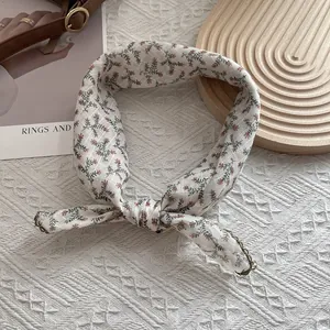 Detail of floral silk scarf with fine edge stitching and soft red flower patterns