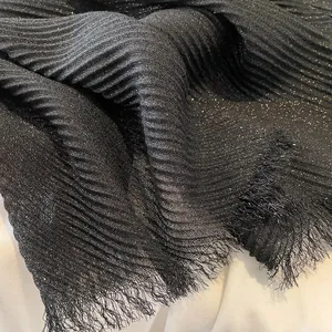 Detail of black pleated cotton linen scarf with sparkling gold dusting and fringe edges