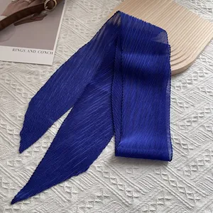 Detailansicht eines royalblauen Falten-Langschals auf Holzbrett und Strick-Hintergrund