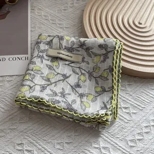 Detail of floral scarf with lemon prints and crochet lace edges on a wooden tray