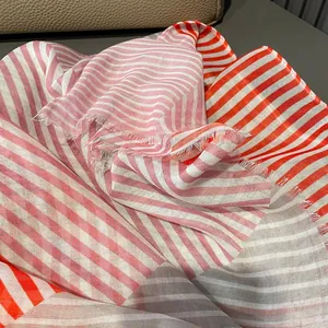Detail of lightweight striped scarf with orange and grey patterns and fringe edges