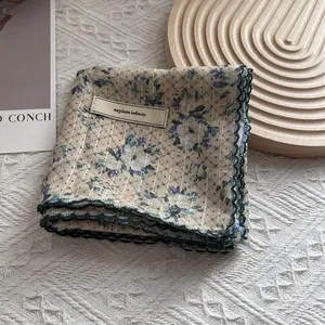 Detail of floral silk scarf with scalloped green edges and explore infinity woven label