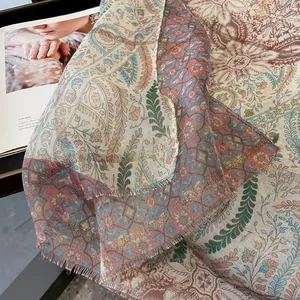 Detailed close-up of paisley floral scarf with golden metallic threads and frayed edges