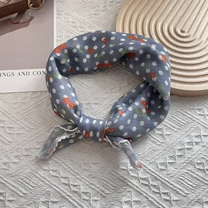Detail of blue floral silk scarf featuring red cherry patterns and fine hemmed edges