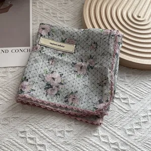 Detail of floral cotton scarf with pink crochet lace edge and decorative cloth label