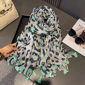 Green leopard print scarf with fringe tassels on a stylish desk setting