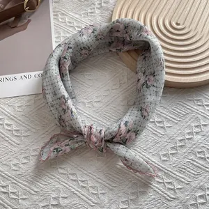 Detail view of floral silk scarf with pink lace edges and delicate flower pattern print