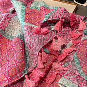 Détail d'une écharpe bohème rose et verte avec des franges fines et des glands doux