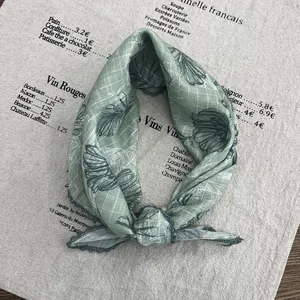 Close-up of lightweight green cotton linen scarf with vintage floral patterns and hem details
