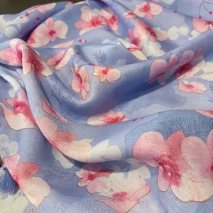 Détail de l'imprimé floral rose sur écharpe bleu clair avec texture sergée et glands