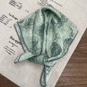 Close-up of light green cotton scarf featuring black floral print and scalloped lace edges