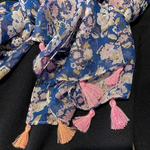Detail of blue floral print scarf with soft pink and orange tassel fringe edges