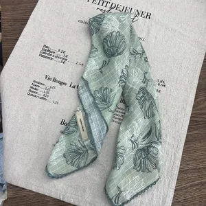 Detail of green floral silk scarf with lace trim and elegant tulip pattern on fabric