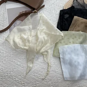 Foulards en soie florale en cinq couleurs sur fond blanc avec un sac en cuir marron