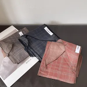 Pañuelos de lino a cuadros marrones, azules y rojos sobre fondo de cuero con decoración