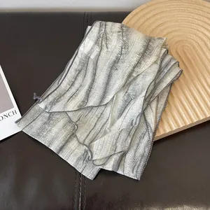 Detail showing the thin chiffon texture and gray abstract tie-dye stripes of the scarf