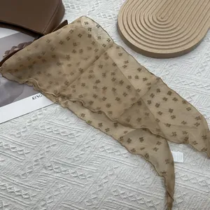 Détail d'une écharpe en mousseline fleurie kaki avec des accessoires vintage