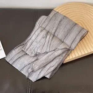 Detailed view of gray tie-dye pleated scarf fabric with bark-like texture on leather base