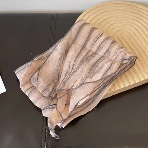 Detail showing the thin tie-dye striped silk scarf texture on a wooden tray