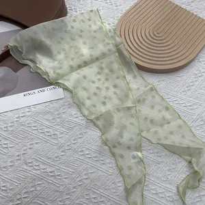 Vue détaillée d'un foulard en mousseline vert clair avec fleurs 3D et bords aux finitions fines