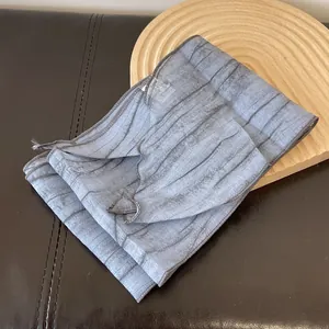 Close-up of gray-blue tie-dye striped silk scarf with sheer pleated texture and hem detail