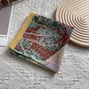 Detail of a vintage artistic print silk scarf with yellow hem on white textured fabric