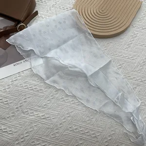 Détail d'un foulard floral translucide avec bords festonnés sur fond texturé