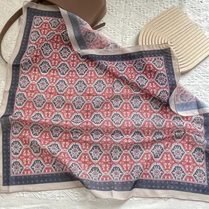Elegantes Seidentuch mit Blumenmuster auf einer braunen Ledertasche im Retro-Stil
