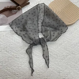 Détail de l'écharpe en organza gris avec bords festonnés et motifs fleuris rétro