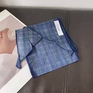 Detalle de la bufanda de lino azul marino con costura fina y etiqueta de material