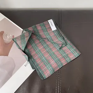 Detalle de bufanda de lino con cuadros verdes y rosas y etiqueta de material cosida
