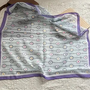 Detail eines hellblauen Seidentuchs mit Vintage-Medaillons und violettem Rand