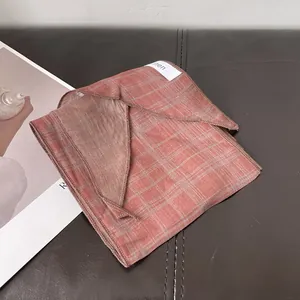 Detalle de bufanda de lino a cuadros sobre base de cuero con revista de moda de fondo