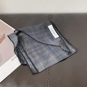 Detalle de una bufanda de lino plegada con cuadros azules y amarillos sobre cuero marrón