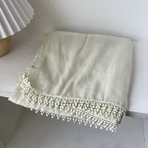 Châle en coton et lin vert clair avec dentelle crochetée sur une table en bois chic
