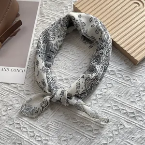 Détail d'un foulard carré blanc à motifs paisley noirs avec des bords roulés soignés