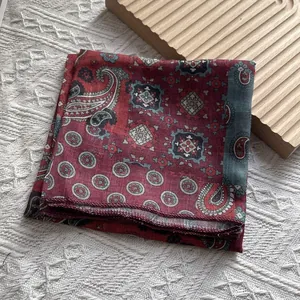 Detail view of red paisley cotton linen scarf with vintage bohemian patterns on knit background